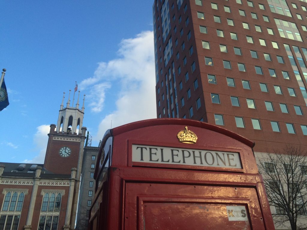 a picture of a English looking telephone booth against the CIty Hall Tower in Manchester, NH